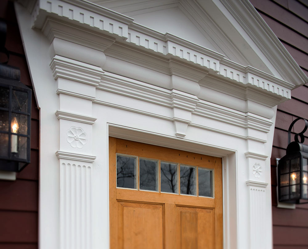 Classical white trim surrounding a wood carriage door with lanterns